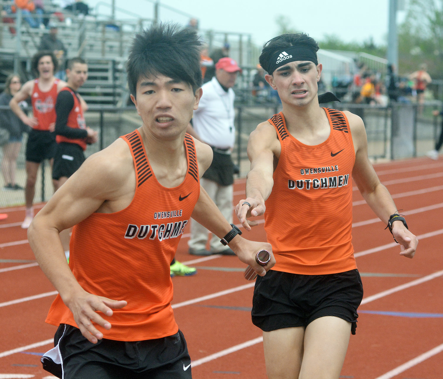Freddy Zheng (left) grabs the baton from Lucas Morgan during the varsity boys 4x800m relay in Monday’s FRC track meet at Dutchmen Field.